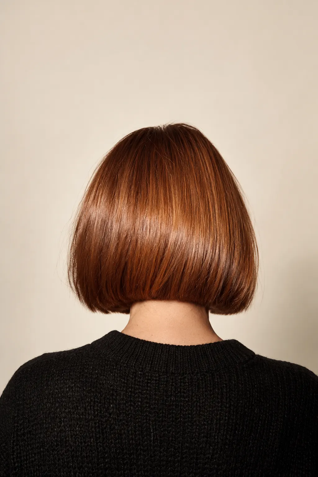 The back of a glossy copper blunt bob, cut level at the jaw
